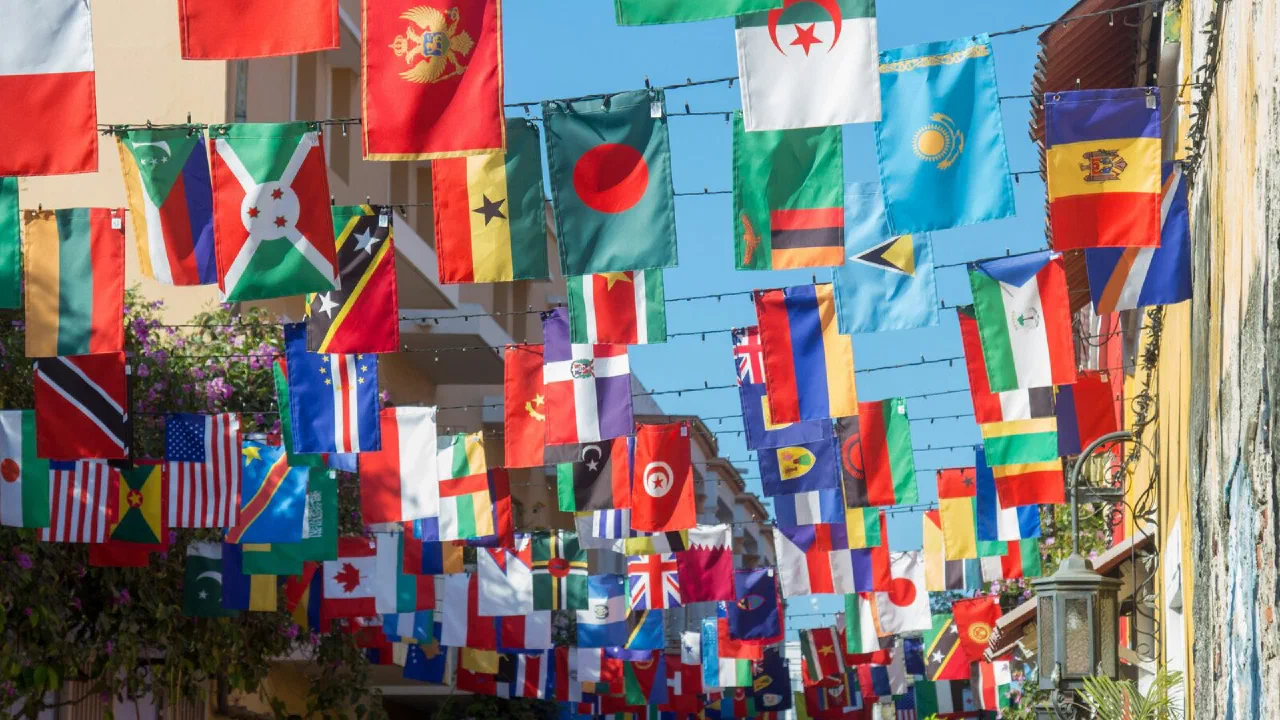 Rows of national flags hanging side by side against a pale sky