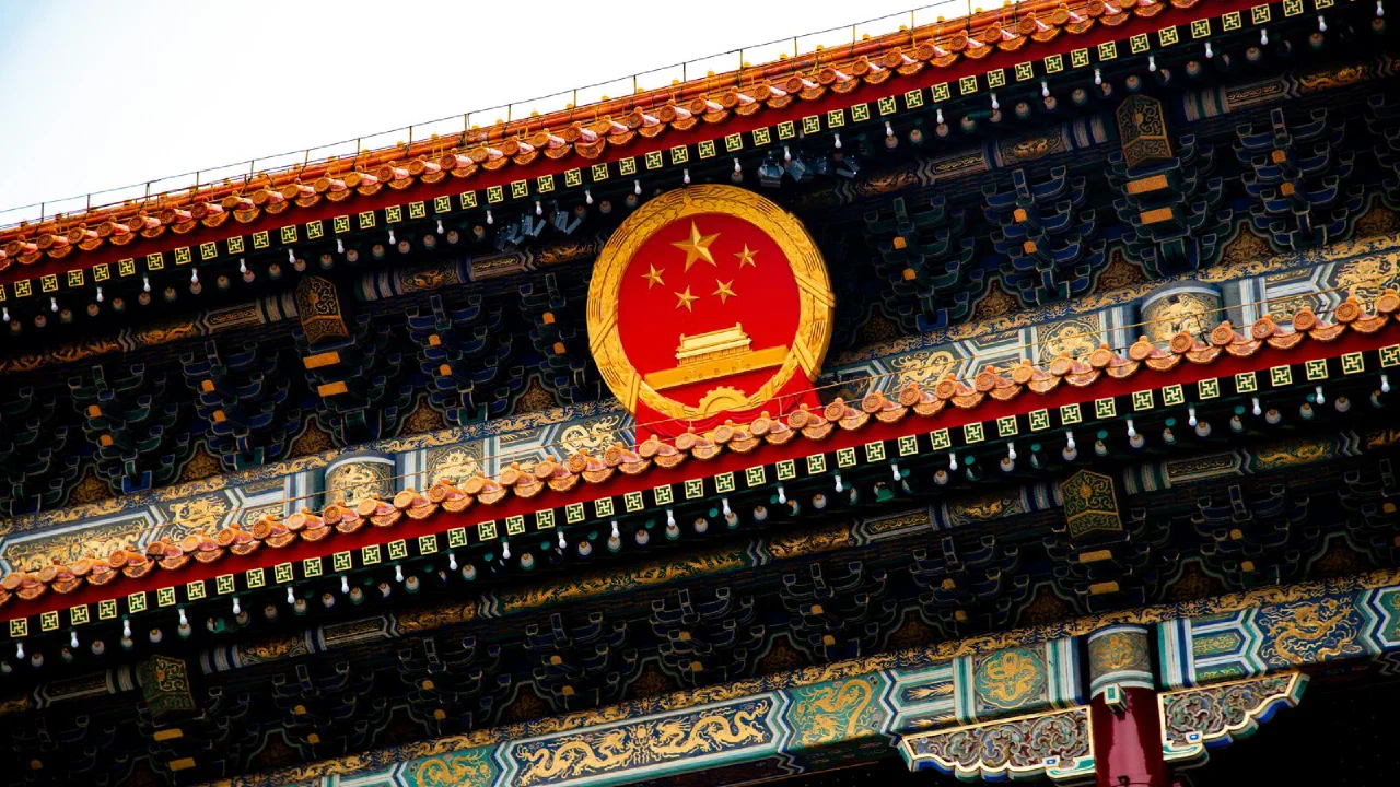 A national emblem mounted on the facade of an ornate traditional Chinese building
